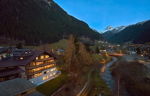 A multi-story building with balconies, a river, and a mountain backdrop. - Suite With Private Sauna (Gaschurn)