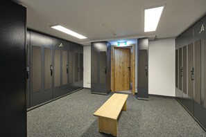 A locker room with multiple lockers, a wooden bench, and a door leading to another room. - Suite With Private Sauna (Gaschurn)