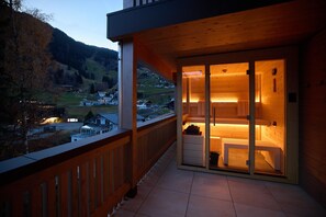 A wooden balcony with a view of a hillside village. - Suite With Private Sauna (Gaschurn)