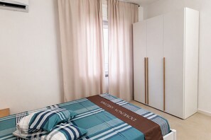 Een slaapkamer met een bed, gordijnen, een kledingkast en een radiator.