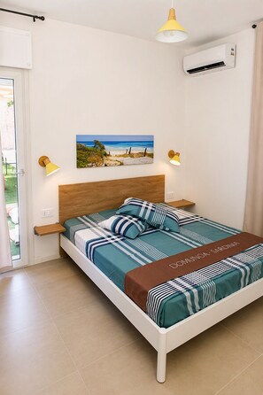 Ein Schlafzimmer mit einem Bett, Nachttischlampen, einem Bild an der Wand und einer Klimaanlage.