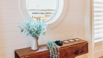 A wooden console table with a mirror, a vase with greenery, and a hanging plant.