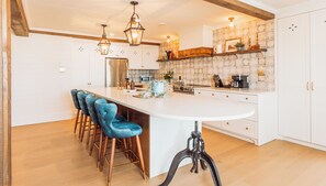 Une cuisine moderne dotée d’un îlot central, de tabourets de bar et de luminaires suspendus.