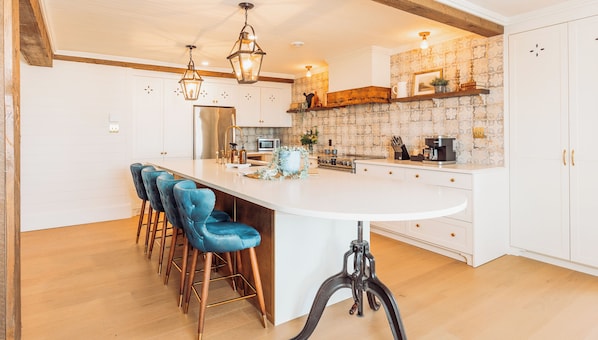 Una cocina moderna con una isla central, taburetes de bar e iluminación colgante.