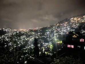A densely populated hillside cityscape at night with numerous lights.