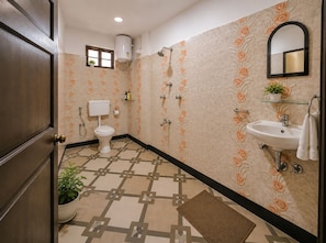 A bathroom with a toilet, sink, shower, and a potted plant.