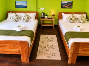 Ein Hotelzimmer mit zwei hölzernen Betten, grünen Wänden und einem kleinen Tisch mit Wasserkocher und Blumen.