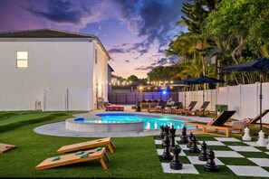 A backyard with a swimming pool, outdoor seating, and a chessboard. - Saltwater Pool -12Hole Miniature Golf & Pickleball (South Miami Heights)