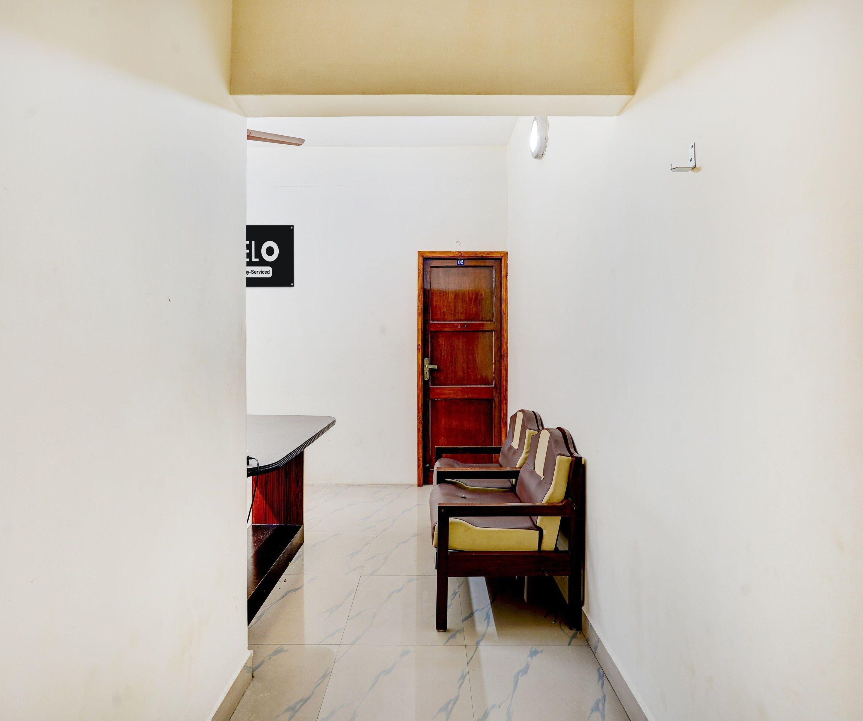 A narrow hallway with a wooden door, a bench, and a small table.