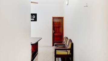 A narrow hallway with a wooden door, a bench, and a small table.