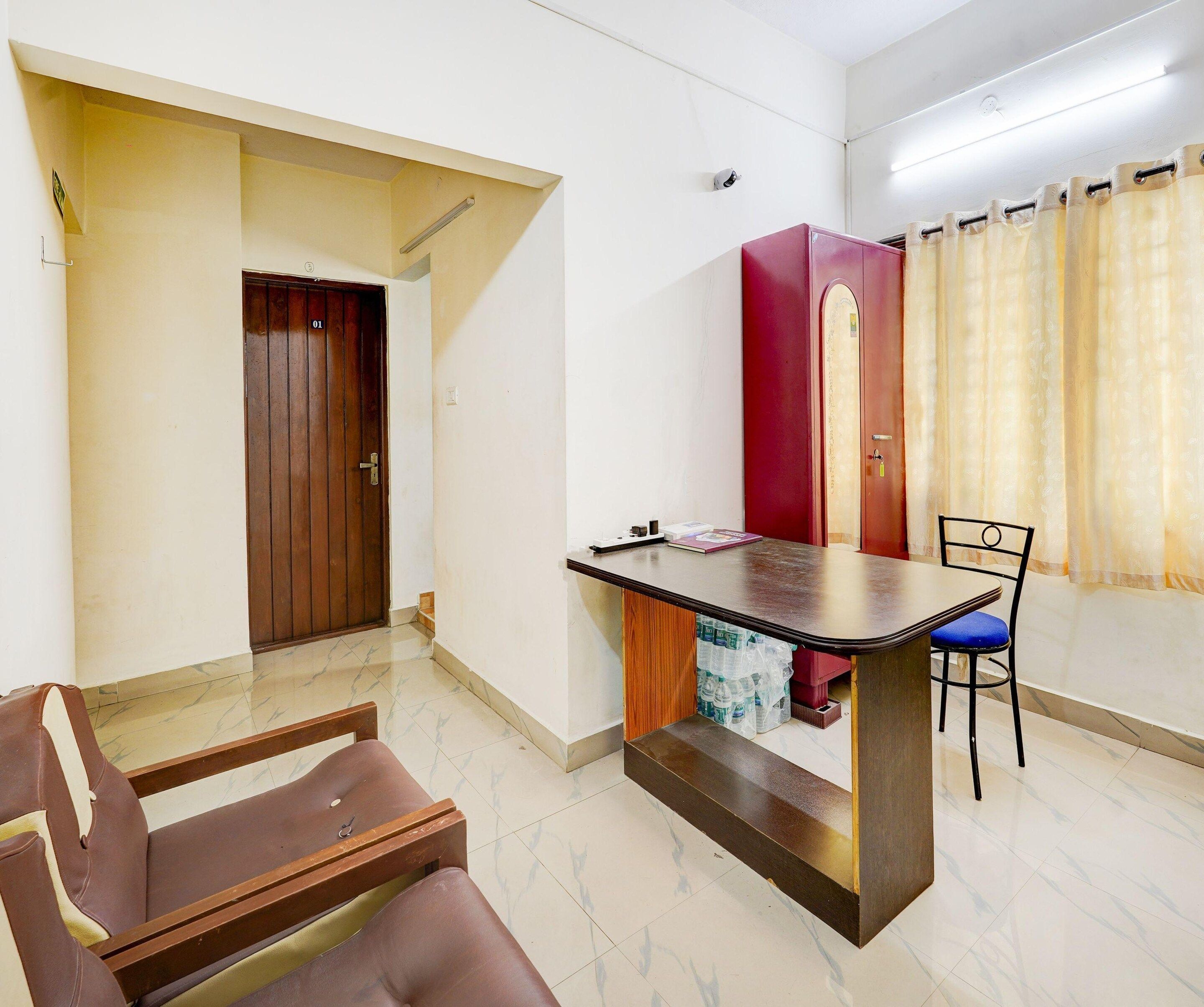 A room with a wooden door, a red cabinet, a table with a chair, and a window with curtains.
