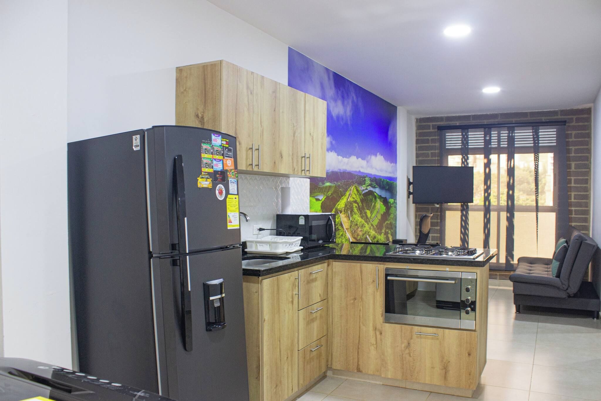 Una cocina compacta con refrigerador, microondas, estufa y armarios de madera.