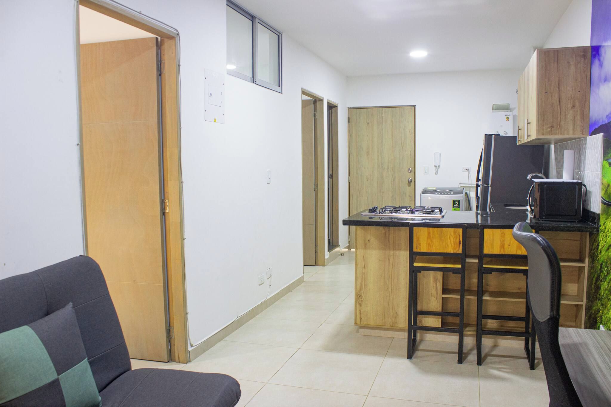 Un espacio habitable compacto con kitchenette, un sofá y una pequeña zona de comedor.