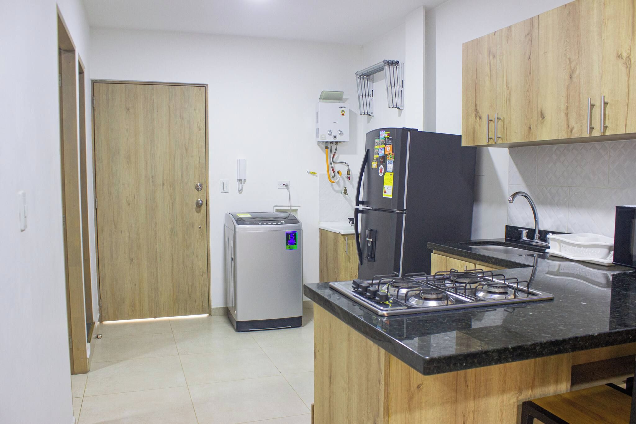 Una cocina compacta con refrigerador, estufa y lavadora pequeña.