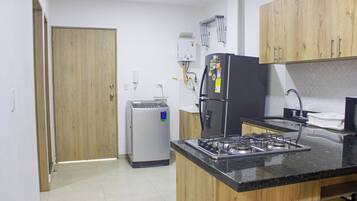 Una cocina compacta con refrigerador, estufa y lavadora pequeña.