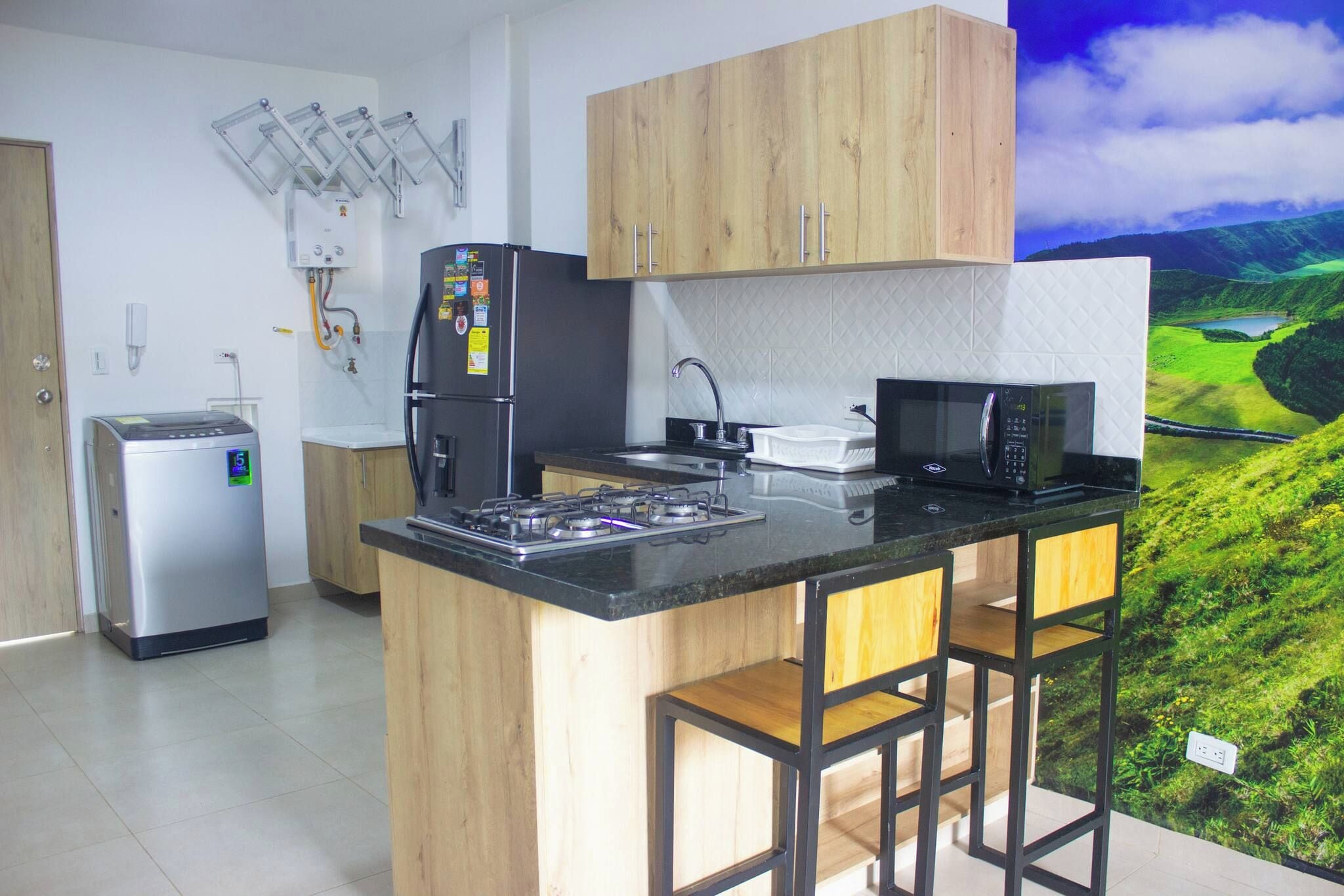 Una cocina moderna con una isla central, electrodomésticos de acero inoxidable y vistas a un paisaje verde.