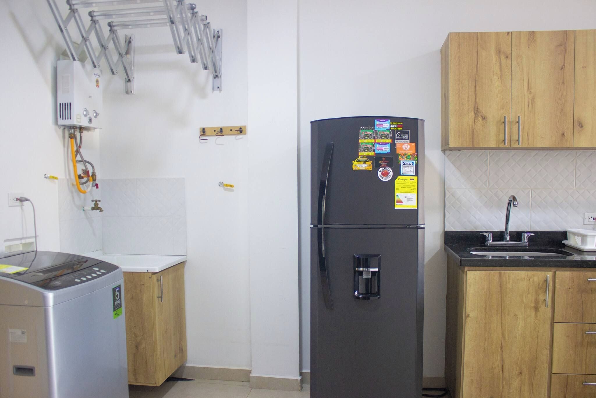 A kitchen with a refrigerator, a coffee maker, wooden cabinets, and a sink.