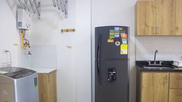 A kitchen with a refrigerator, a coffee maker, wooden cabinets, and a sink.