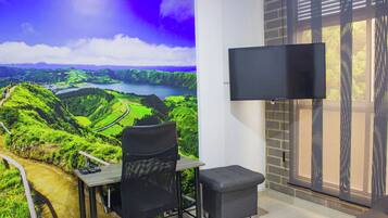 Una habitación con escritorio, silla y televisor de pantalla plana montado en la pared.