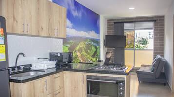 Una cocina moderna con armarios de madera, horno empotrado, estufa a gas y televisor de pantalla plana montado en la pared.