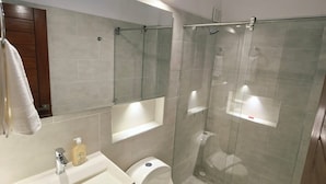 A modern bathroom with a glass shower enclosure, a white toilet, and a vanity with a mirror. - Hotel Calle Real de la Villa (Villa de Leyva)
