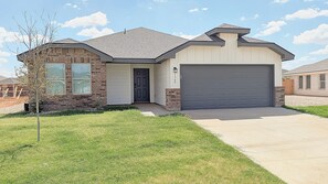 A residential house with a garage, a front door, and a small lawn. - Modern Midland Retreat (Midland)