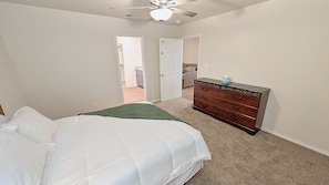A bedroom with a bed, dresser, and a ceiling fan. - Modern Midland Retreat (Midland)
