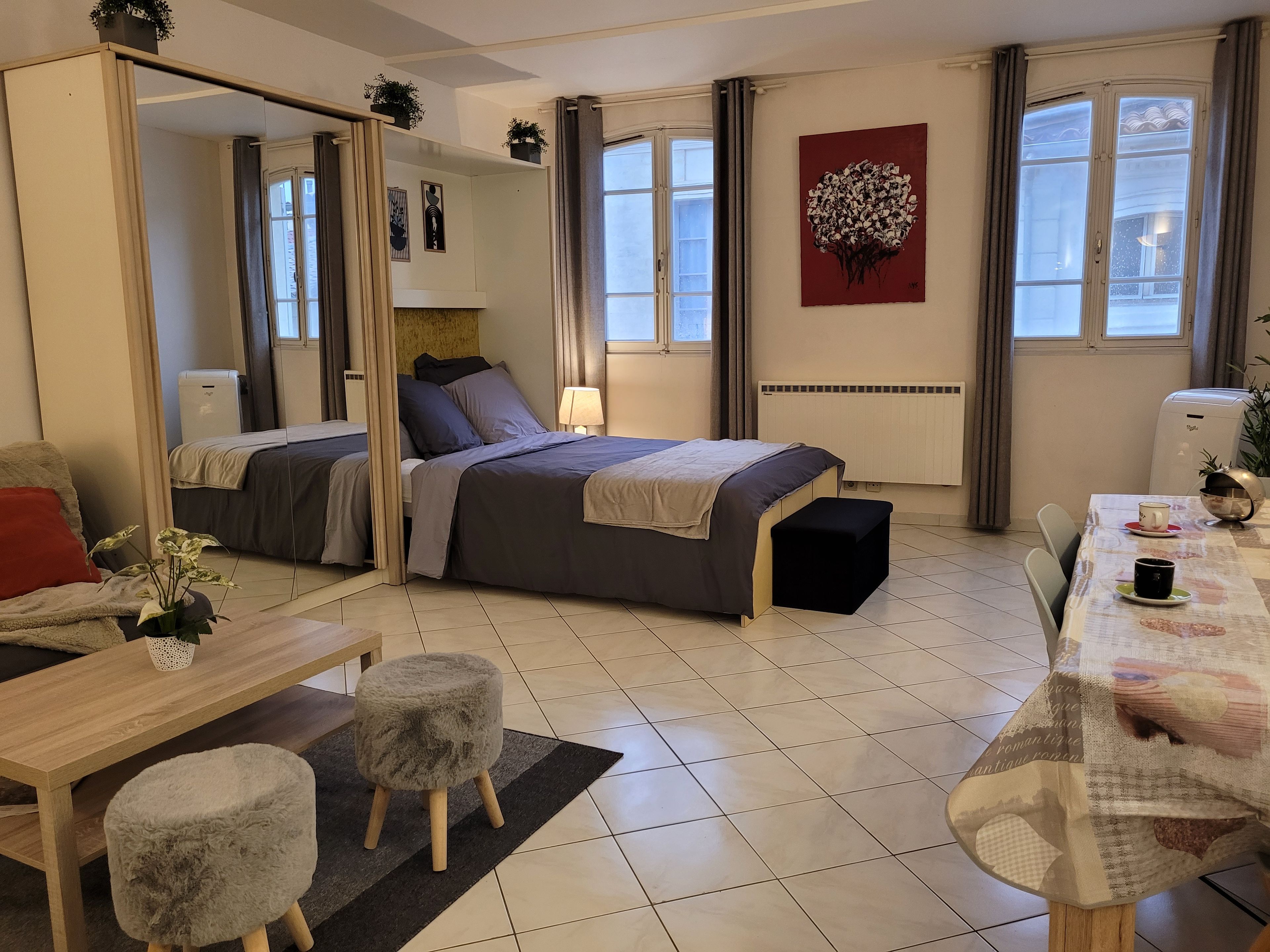 A modern hotel room with a bed, bedside table, chair, and a dining area.