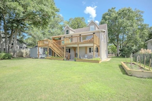 A two-story house with a wooden deck and a covered porch. - Asleep At The Reel: Waterway Home with Dock (Oak Island)