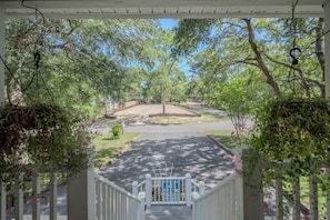 A covered outdoor area with a wooden staircase leading to a gated entrance. - Asleep At The Reel: Waterway Home with Dock (Oak Island)