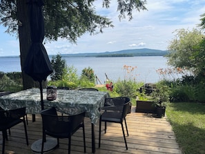 Ein Essbereich im Freien mit Tisch und Stühlen, einer Holzterrasse und Blick auf einen See.