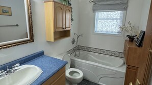 Un baño con lavamanos, inodoro, bañera y ventana con cortina.