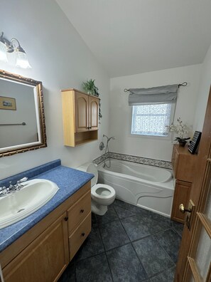 Ein Badezimmer mit Waschbecken, Toilette, Badewanne und einem Fenster mit Vorhang.