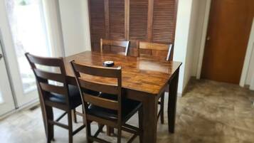 Une table à manger avec six chaises, une fenêtre avec des stores et une porte.