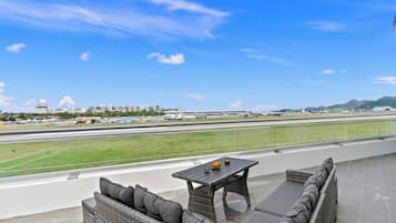 Área de estar ao ar livre com vista para um aeroporto e montanhas distantes.