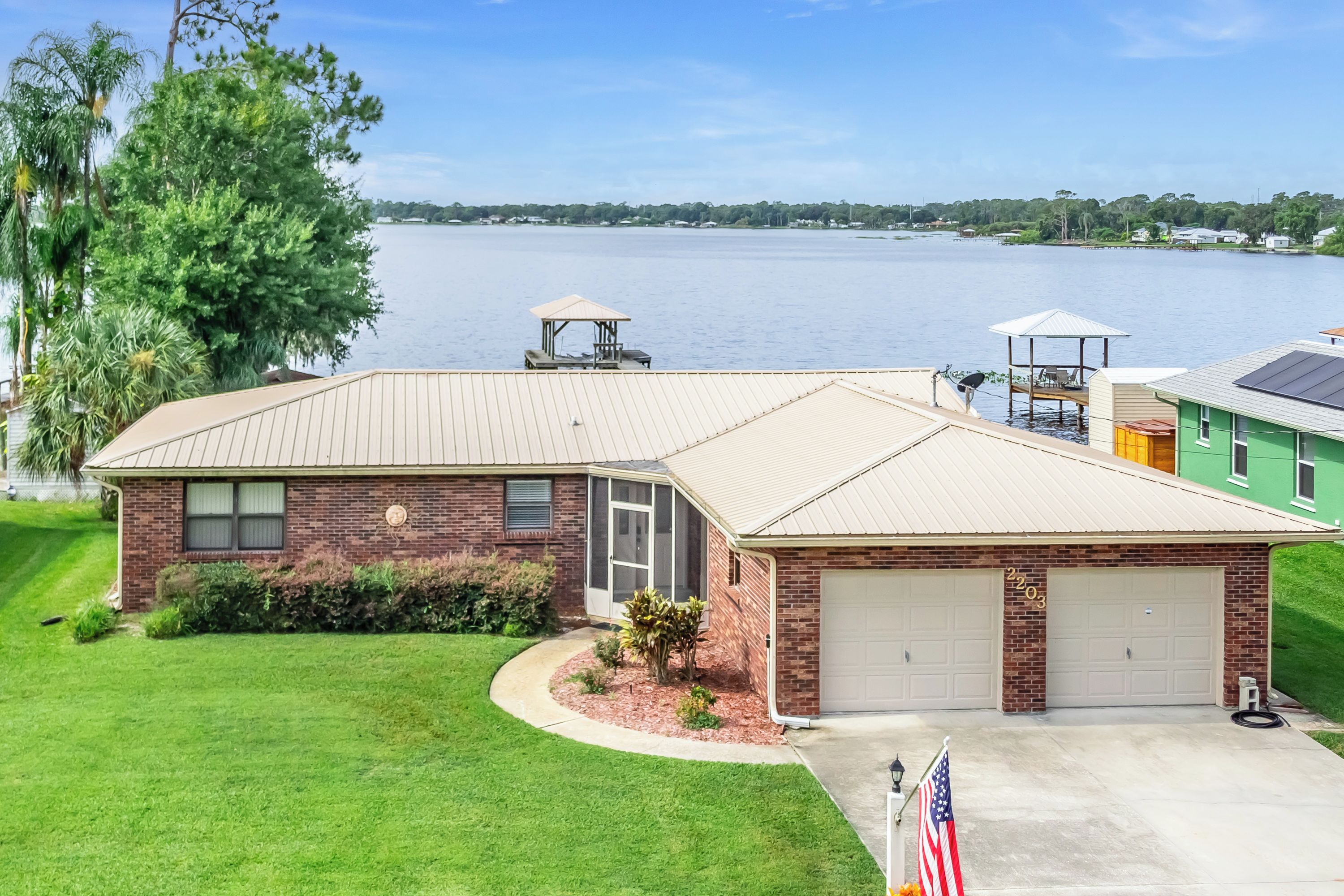 A two-story house with a garage, a covered patio, and a view of a lake.