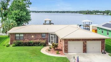 A two-story house with a garage, a covered patio, and a view of a lake.