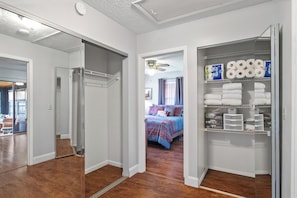 Ein Hotelzimmer mit begehbarem Kleiderschrank, einem Bett mit gemustertem Überwurf und einem Badezimmer mit Dusche und Toilette.