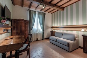Une pièce comprenant une table à manger en bois, des chaises, un canapé, un meuble en bois et une fenêtre avec des rideaux.