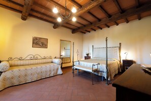 Un dormitorio con cama con dosel, una cama tipo diván, un espejo y una araña.