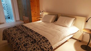 Un dormitorio con cama, mesita de noche y vistas a un balcón.