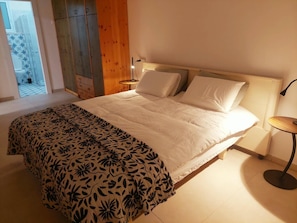 A bedroom with a bed, a bedside table, and a view of a balcony. - 2-bedroom villa in adorable Mitzpe Ramon with privet pool and beautiful garden (Mitzpe Ramon)