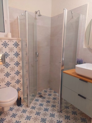 A bathroom with a glass-enclosed shower, a toilet, and a sink with a mirror above it. - 2-bedroom villa in adorable Mitzpe Ramon with privet pool and beautiful garden (Mitzpe Ramon)
