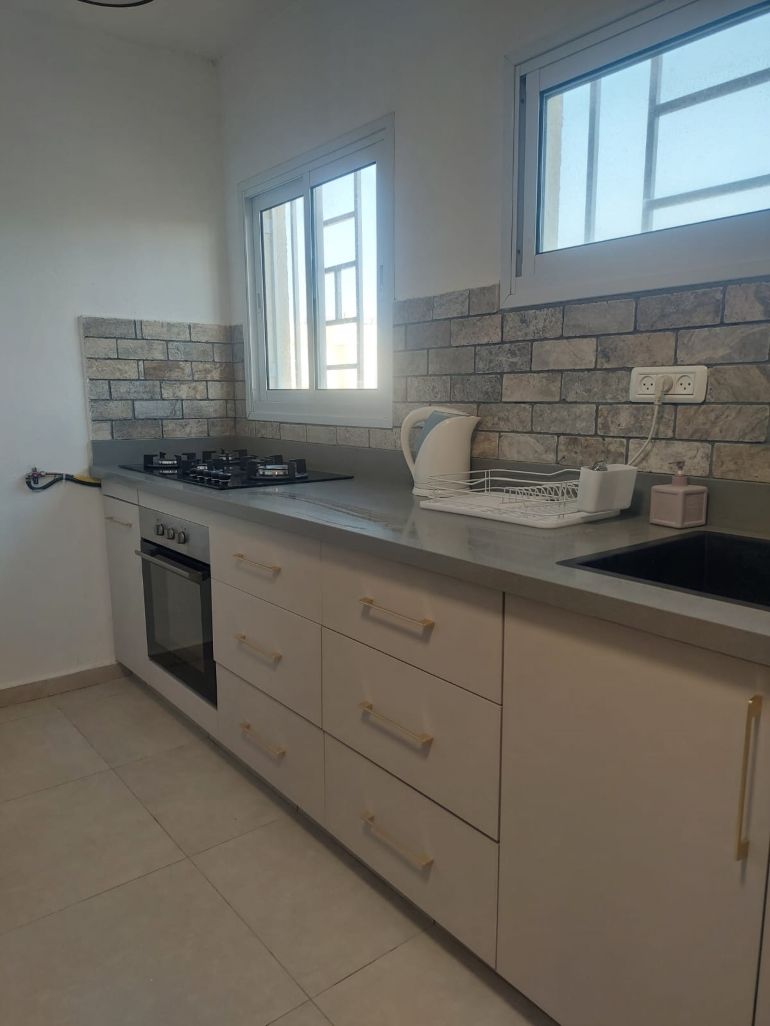 A kitchen with a gas stove, oven, and a window above the sink.