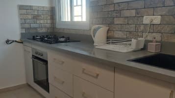 A kitchen with a gas stove, oven, and a window above the sink.