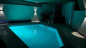 Una piscina con una escalera metálica, rodeada por una terraza de madera.