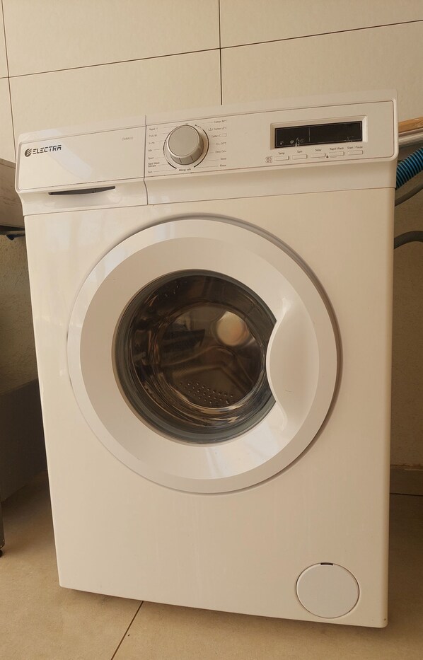 A front view of a white washing machine with a control panel on top, a digital display, and a front-loading door.