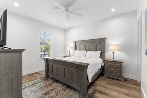 A bedroom with a bed, nightstands, a ceiling fan, and a window. - Ocean Breeze: Heated Pool & Hot Tub, Free Golf Cart, Two Arcade Rooms (Miramar Beach)