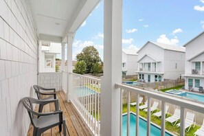 A balcony with a view of a swimming pool and adjacent houses. - Ocean Breeze: Heated Pool & Hot Tub, Free Golf Cart, Two Arcade Rooms (Miramar Beach)