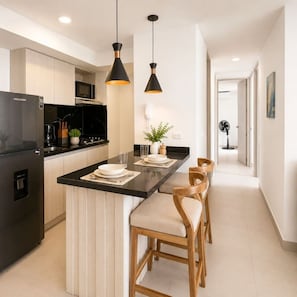 A modern kitchen with a central island, black appliances, and pendant lighting. - Tropical Midnight | Sunset Views & Pool, Wi-Fi (Cartagena)
